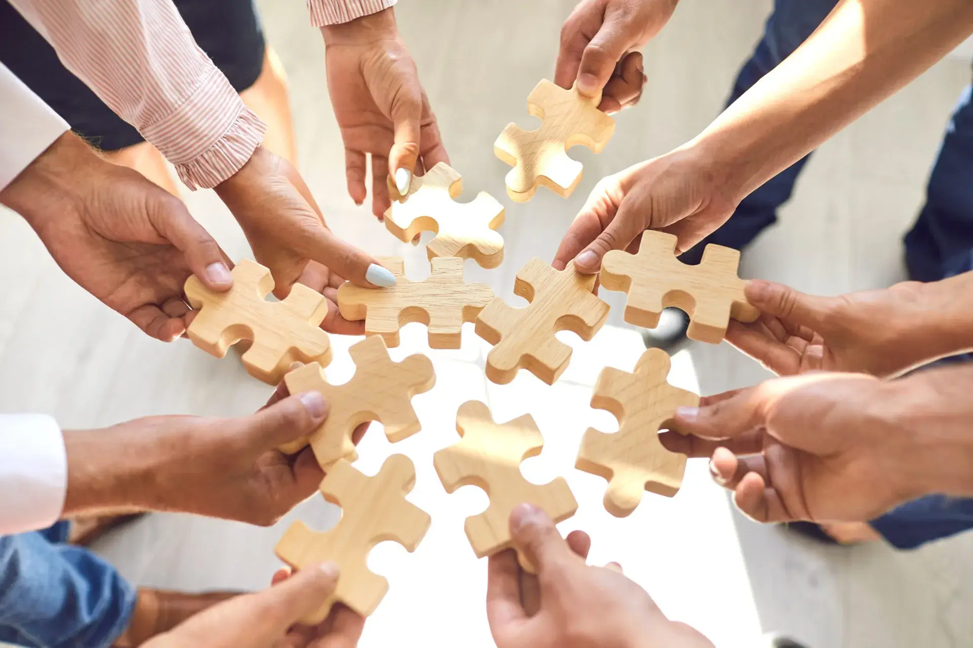 Hands bringing wooden puzzle pieces together