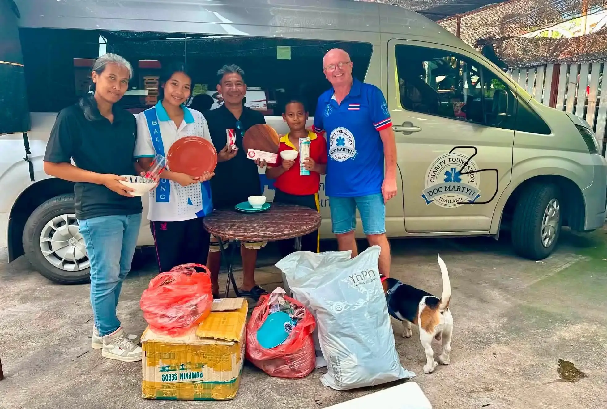 A group standing beside a van with bags and household items