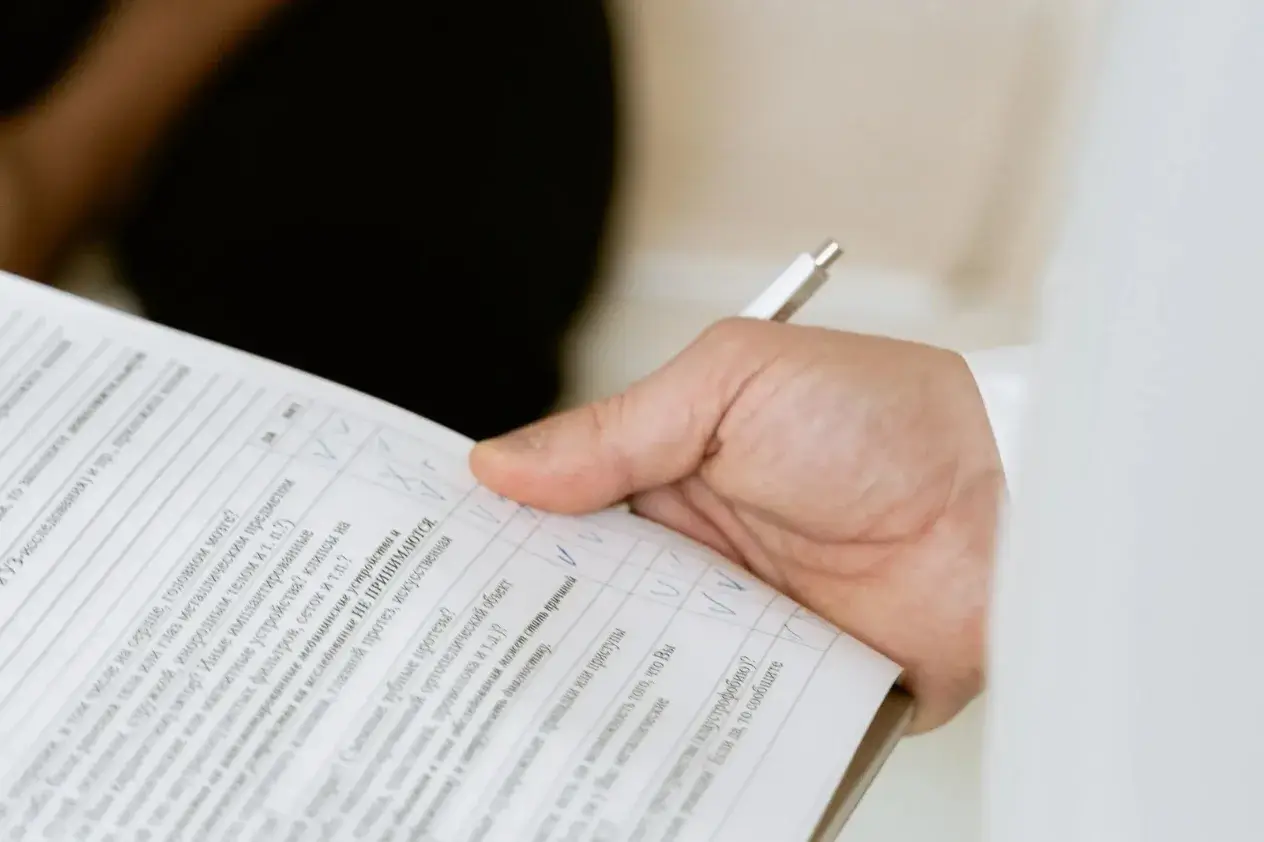 A person holding a pen and a medical assessment form